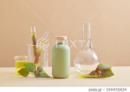 Empty label cosmetic bottle displayed with several glassware in the laboratory room. There are many methods of applying Beefsteak Plant (Perilla frutescens) leaves in skin beauty 104458834