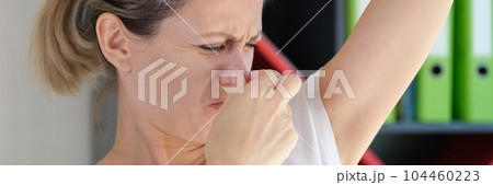 Young woman sniffing armpits and covering nose 104460223