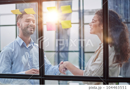 Creative professionals standing and discussing in office behind glass wall with sticky notes 104463551