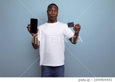 30 year old american male adult manager in white t-shirt showing smartphone screen and shopping card 104464491