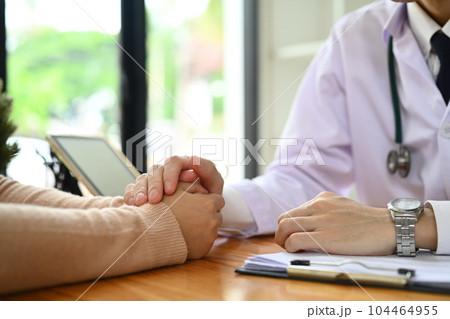 Doctor doctor in white uniform holding hands of female patient, showing support, express sympathy, trust and encourage Doctor doctor in white uniform holding hands of female patient, showing support, express sympathy, trust and encourage 104464955