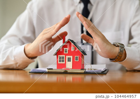 Man hands protecting over little house. Property insurance and security concept Man hands protecting over little house. Property insurance and security concept 104464957