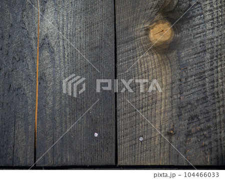 Background from burnt boards. Texture of burnt wood. Black wood wall. Boards after the fire.  Nails 104466033