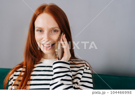 Closeup portrait of pretty young woman talking on smartphone smiling looking at camera. Cheerful female making answering call by cellphone. Positive lady having pleasant conversation speaking by phone 104466998