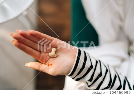 Closeup top view cropped shot of unhappy depressed millennial female hold pills in hand and thinking about suicide. Concept of many problems, overdose and mental disorder, pain and crisis. 104466999