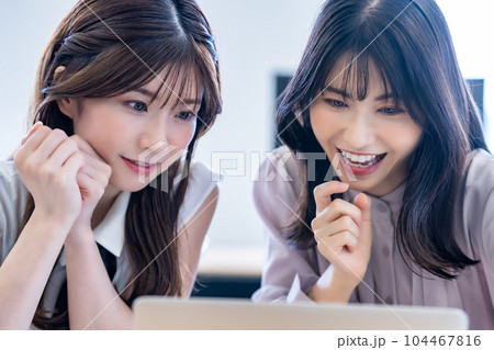 オフィスで休憩時間に旅行の計画をする二人の女性 オフィスで休憩時間に旅行の計画をする二人の女性 104467816
