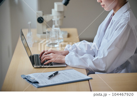 パソコンをタイピングする白衣の若い女性 104467920