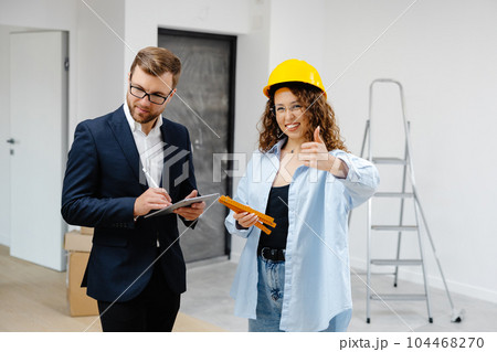 Young designer and customer businessman are designing interior standing with digital tablet in the new living room interior 104468270