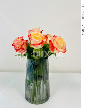 Bouquet of beautiful roses housed in a glass vase in the office. 104469015