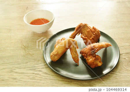 crispy fried chicken wing on black plate dipping with sweet chili sauce  104469314