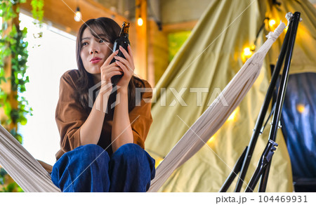 キャンプでビールを片手に微笑む若い女性 ハンモック キャンプでビールを片手に微笑む若い女性 ハンモック 104469931