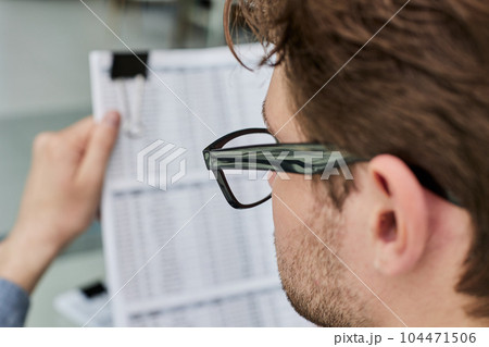 Close-up of a financial businessman holding an information sheet in his hands, reading the company's financial statements for making a financial plan. Close-up of a financial businessman holding an information sheet in his hands, reading the company's financial statements for making a financial plan. 104471506