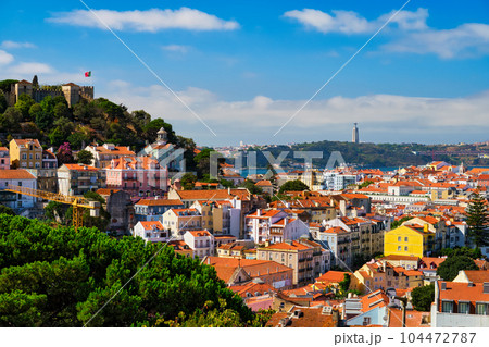 Lisbon famous view from Miradouro dos Barros tourist viewpoint over Alfama old city district with St. George's Castle and Portugal flag, 25th of April Bridge, Christ the King statue. Lisbon, Portugal. Lisbon famous view from Miradouro dos Barros tourist viewpoint over Alfama old city district with St. George's Castle and Portugal flag, 25th of April Bridge, Christ the King statue. Lisbon, Portugal. 104472787