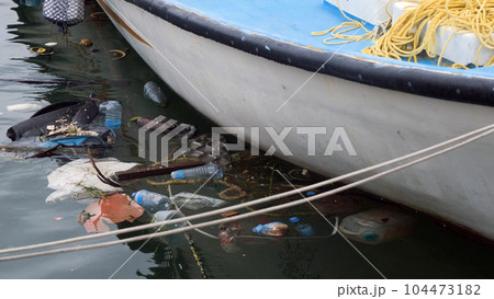 Close-up of lots of trash and plastic bottles near the moored fishing boat. Environmental pollution concept 104473182