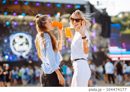 Two woman having great time at music festival. Girlfriends rinking beer at Beach party. Lifestyle. Two woman having great time at music festival. Girlfriends rinking beer at Beach party. Lifestyle. 104474177