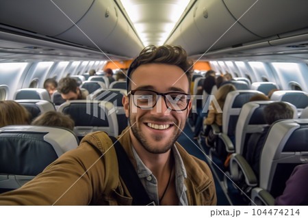 A handsome man taking a selfie with a mobile phone on board of plane. Smiling people having fun flying during the time on the airplane. Concept of happiness on airplane 104474214