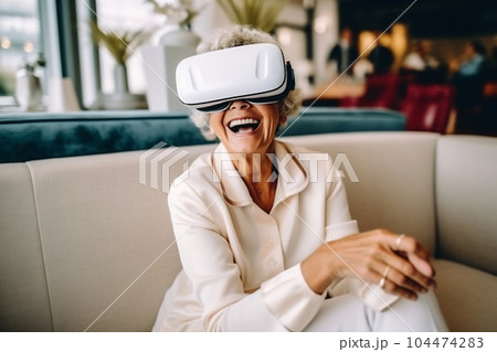 Senior mature female having fun with virtual reality glasses. Old woman using new headset goggles trends technology 104474283
