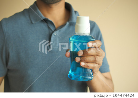 hand hold a mouthwash liquid container  104474424