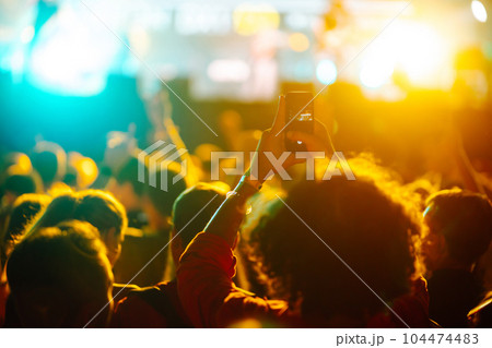 People taking photograph with phone during music festival Fans enjoying rock concert with light show People taking photograph with phone during music festival Fans enjoying rock concert with light show 104474483