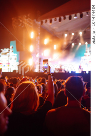 People taking photograph with phone during music festival Fans enjoying rock concert with light show 104474484