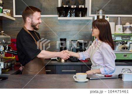Colleagues, partners, man and woman shake hands, in coffee shop 104475461