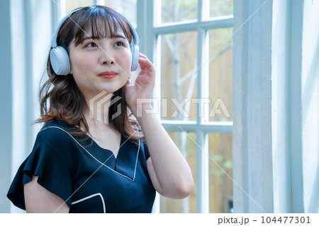 ヘッドホンで音楽を聴く若い女性 104477301
