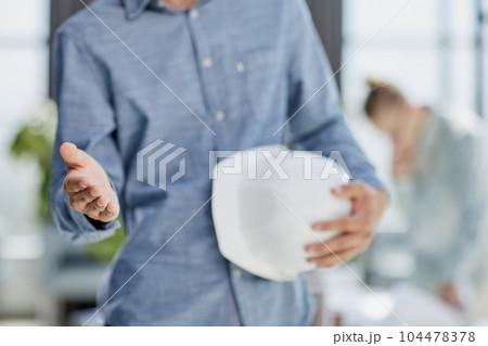 Architect and civil engineer shaking hands while holding hard hat in hand Architect and civil engineer shaking hands while holding hard hat in hand 104478378