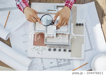 Male architect holding and working on model of architectural house top view Male architect holding and working on model of architectural house top view 104478821