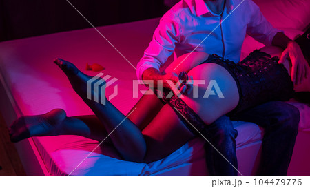 A man with a mistress on his knees holds an anal plug in the bedroom. A man with a mistress on his knees holds an anal plug in the bedroom. 104479776