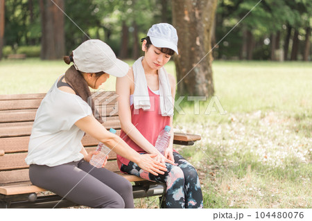 運動・ジョギング・有酸素運動中に膝を痛めたアジア人女性と心配する友達・ママ友 104480076