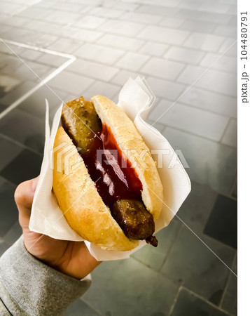 シンプルなドイツ式ホットドッグを手に持っている男性 シンプルなドイツ式ホットドッグを手に持っている男性 104480791