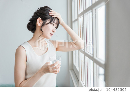 朝、体調不良・発熱・偏頭痛に悩むアジア人の女性 104483305