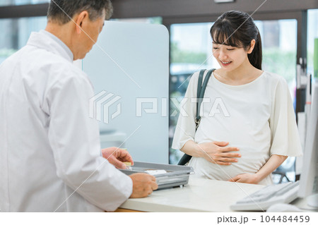 薬局に来た妊婦と服薬指導する薬剤師（妊婦・授乳婦薬物療法認定薬剤師） 104484459