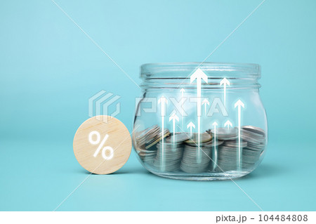 Wooden block with percentage sign and jar of coins 104484808
