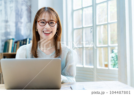部屋でノートパソコンを使う眼鏡をかけた若い女性 部屋でノートパソコンを使う眼鏡をかけた若い女性 104487801