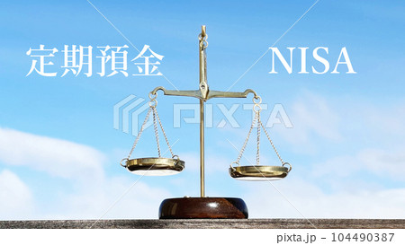 定期預金とNISAの文字と金天秤と青空 104490387