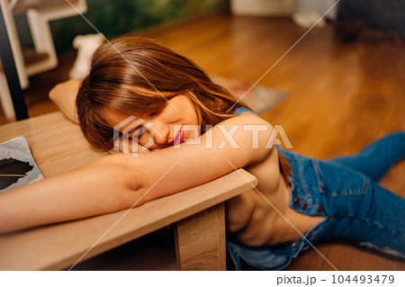 a naked woman in denim jumpsuit lying on the floor near the coffee table 104493479