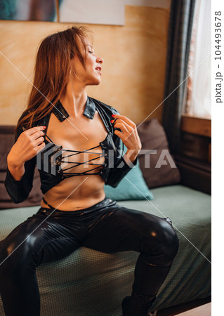 Playful attractive sexy young woman in black leather suit. 104493678
