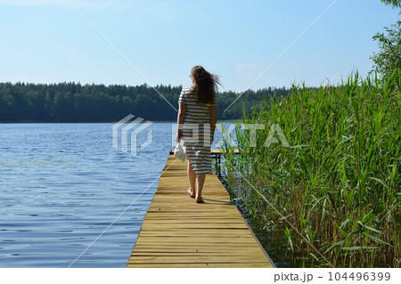 Girl on the pier on a sunny summer day. 104496399