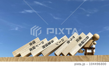 倒れるたくさんの板と前向きで受け止める人形_借金関連文字入り 104496800