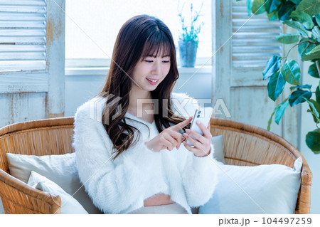 ソファでスマホを使う若い女性 ソファでスマホを使う若い女性 104497259