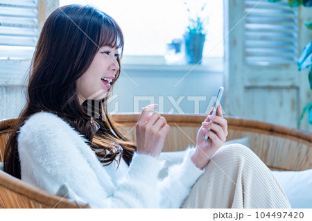 ソファでスマホを使う若い女性 104497420