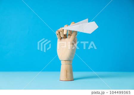 Wooden hand with paper plane on blue background Wooden hand with paper plane on blue background 104499365