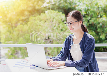 University teen Asian young woman sitting education learning typing laptop computer with green tree background. 104500713