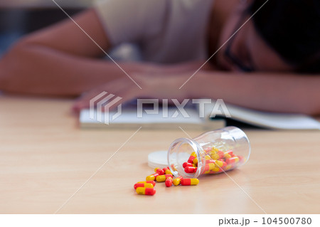Young teen student with medicine drug capsule pill for pain relief or reduce stress from studying hard. Young teen student with medicine drug capsule pill for pain relief or reduce stress from studying hard. 104500780