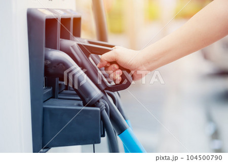 EV charging station dock head hand holding for modern electric car new energy standard for vehicle power. EV charging station dock head hand holding for modern electric car new energy standard for vehicle power. 104500790