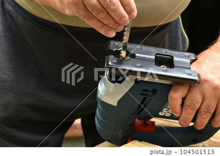 The carpenter is preparing a jigsaw for work. The carpenter is preparing a jigsaw for work. 104501513