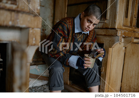 Poor homeless punk woman with sad look eating preserved food 104501716