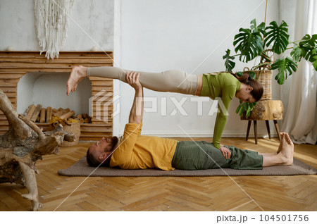 Young couple training yoga in pair doing acrobatic plank together Young couple training yoga in pair doing acrobatic plank together 104501756
