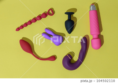 Top view of adult sex toys such as dildo, vibrator, buttplug on yellow background. Sex shop concept 104502110